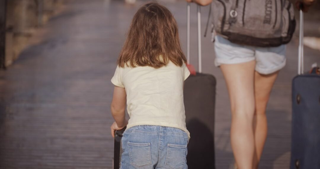 Woman and child walking with luggage while traveling