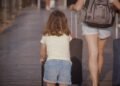 Woman and child walking with luggage while traveling