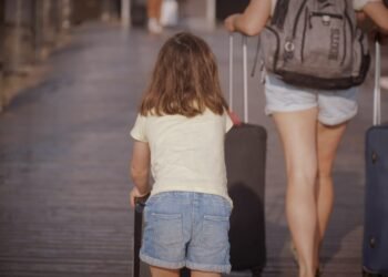 Woman and child walking with luggage while traveling