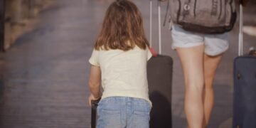 Woman and child walking with luggage while traveling